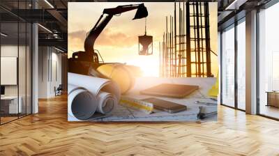 Desk of civil engineer with background silhouette of excavator activity machine Wall mural