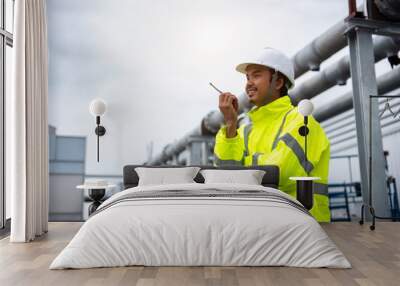 Male Industrial Engineer in the Hard Hat and Wear Yellow Safety Jacket while Standing outdoor at the work plant,  Safety Officer working control. Wall mural