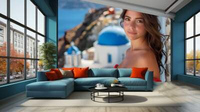 Beautiful young woman tourist on vacation in Greek island Santorini, attractive fashion model smiling in red dress, ocean and blue dome background. Luxury Europe summer travel holiday maker adventure. Wall mural