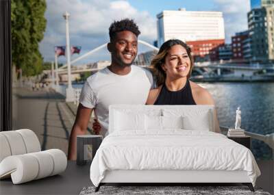 A colorful, urban evening by the riverside with two attractive, diverse models in casual attire, radiating joy. Wall mural