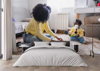 A woman and a baby are playing with toys on a carpeted floor Wall mural