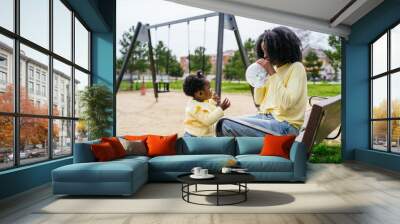 A woman and a child are sitting on a bench in a park with a balloon Wall mural