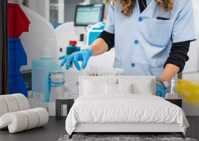 Unrecognizable healthcare worker in lab coat processes blood tests with machinery for simultaneous analysis in a clinical setting Wall mural