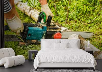 man sawing wood for firewood, using electric chainsaws Wall mural