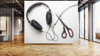 Scissors cut the wire from the headphones, and thus stop the very loud illegal pirated music on a white background Wall mural