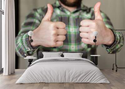 smiling, bearded and happy man in a checkered shirt has made two thumb up Wall mural