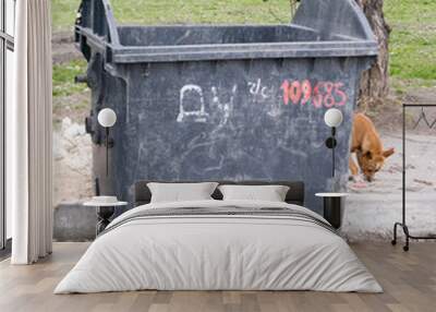 Old empty plastic trash can on wheels Wall mural