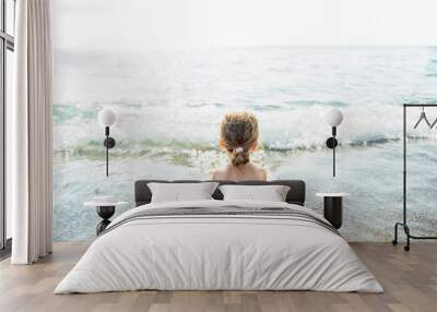 Small girl is relaxing in the sea water with waves on the beach.Summer sunny day.Travel,summer and vacation concept. Wall mural