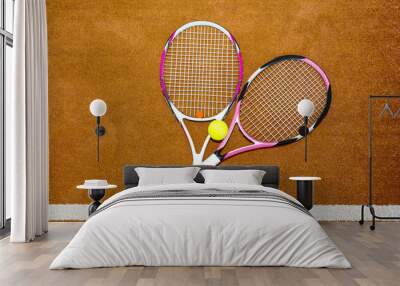 Two new pink tennis rackets with a tennis ball on a clay court o Wall mural