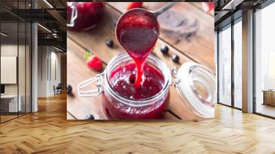 Pouring homemade berry jam into a jar Wall mural