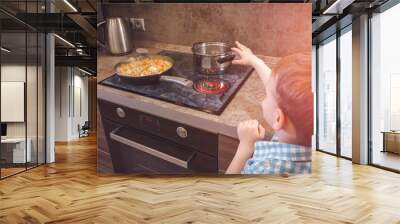 Child reaches for the hot electric stove. Child safety at the kitchen. Wall mural