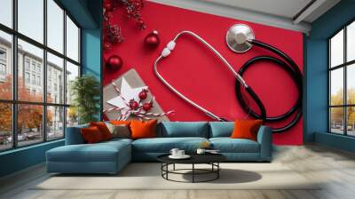 Christmas medical banner. Close up gift box, berries, red balloons and stethoscope on red background, top view, flat lay, copy space. New Year's medicine, congratulations for the doctor. Wall mural