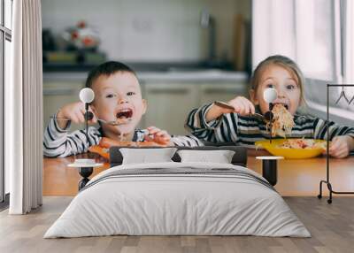 Boy and girl in the kitchen eating pasta screaming with pleasure Wall mural