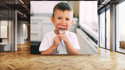 child in the kitchen eating sausage and mashed potatoes Wall mural