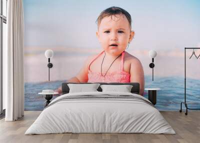 Little girl, baby in pink swimsuit sitting in the sea very happy Wall mural