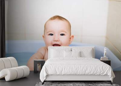 little girl baby is bathed in the blue basin in the bathroom is very fun Wall mural