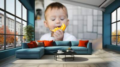 The child in the kitchen eating an orange Wall mural