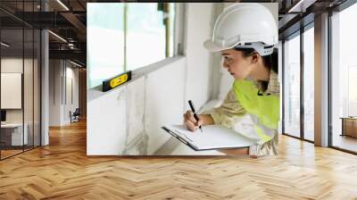 Inspector or engineer checking and measuring the leveling of the wall in the building with checklist and level gauge. Inspection and civil construction concept Wall mural