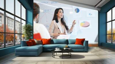 Woman business coach speaker give presentation speaker presenter consulting reporting presenting to CEO or group leader explain graph strategy profit growth result in company meeting  Wall mural