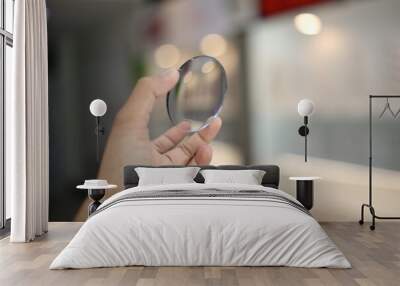 close up of a person holding a magnifying glass, hand holding glasses lens in optical store  Wall mural