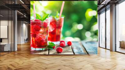 Red raspberry cocktail with soda and ice, green sunny summer garden background Wall mural