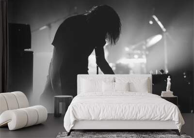 Long hair bass guitarist silhouette on a stage in a backlights playing rock music. Black and white Wall mural