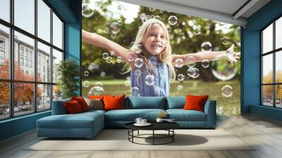 Cute little girl playing soap bubbles Wall mural