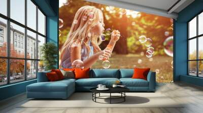 Portrait of a cheerful girl blowing soap bubbles Wall mural