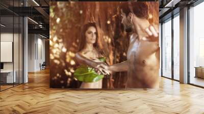 Portrait of two nude lovers walking among tropical trees Wall mural