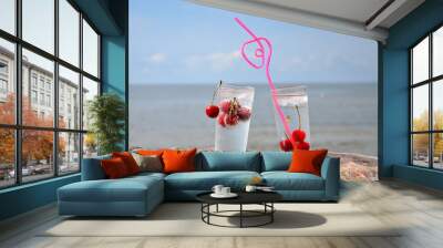 Cherry cold drink with a straw on the background of the sea. Wall mural