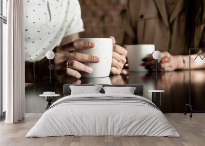 Man and woman drinking coffee. framing on hands. Close up woman and man holding cups of coffee on table Wall mural