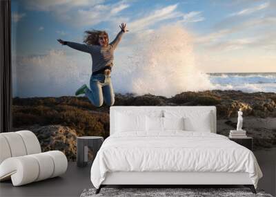 girl jumping on the beach at sunset Wall mural