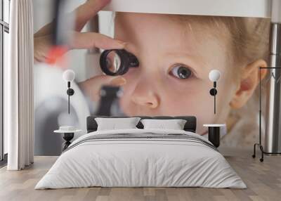 Child's ophthalmology - doctor optometrist checks eyesight for little girl Wall mural