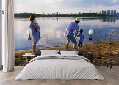 Family fishing on the riverside at sunset - Man with his wife and two chidlren Wall mural