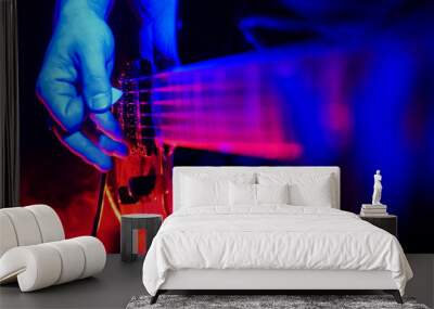 Rock concert. Guitarist plays the guitar. The guitar illuminated with bright neon lights. Focus on hands Wall mural