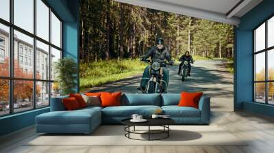 Two bikers are on their bikes riding too fast on the road in forest Wall mural