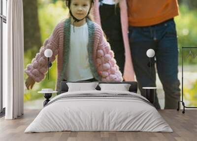 Young happy family of parents and two little kids walking in the forest - a girl skating on the rollers Wall mural