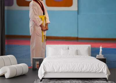 Taekwondo kids. A boy athlete stands in a taekwondo uniform with a yellow belt during a taekwondo tournament Wall mural