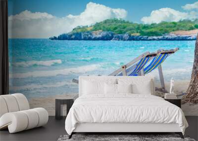 Two wooden loungers with striped seats under a tree, on the tropical beach, Against the backdrop of the waves of the turquoise sea and beautiful delicate aerial cloudy sky. Wall mural