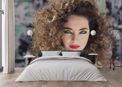 Young beautiful model with bright make-up standing on the street  girl with expressive make-up and curly hair.   Wall mural