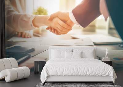 Businessman and businesswoman shaking hands above desk Wall mural