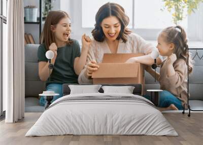 Mother and daughters are unpacking cardboard Wall mural