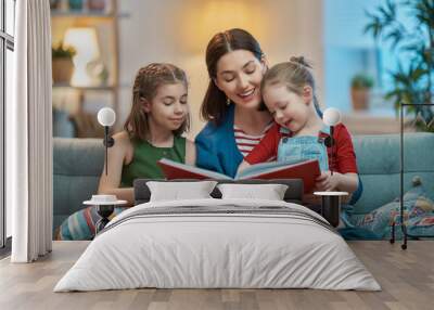 mother reading a book to daughters Wall mural