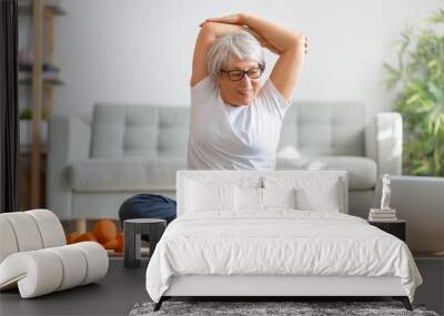 Senior woman exercising at home. Wall mural