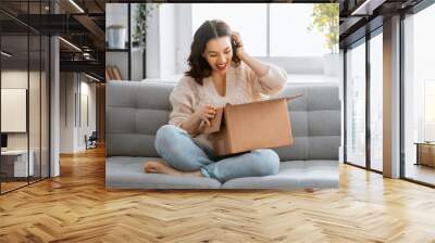 woman is holding cardboard box sitting on sofa at home Wall mural