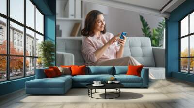 woman is using a phone sitting on a sofa Wall mural