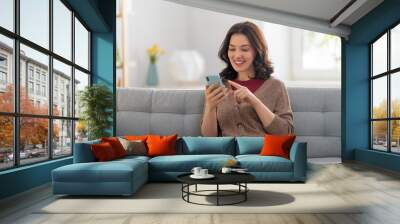 woman is using a phone sitting on a sofa Wall mural