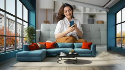 woman is using a phone sitting on a sofa Wall mural