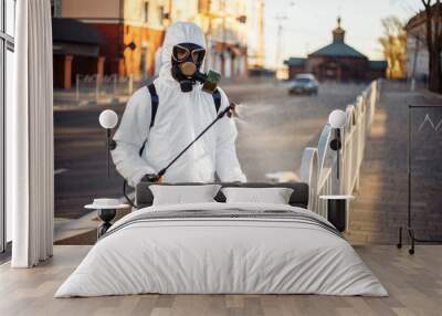 Disinfection team worker is cleaning pavement fence with a sterilizing water spraying it over the coronavirus infected surface. Covid-19 protective equipment and actions to stop spread of the disease. Wall mural