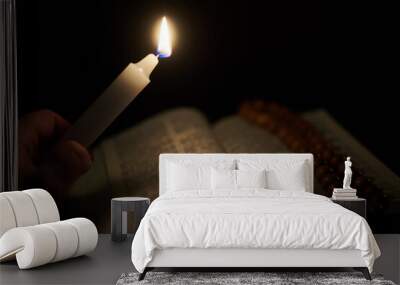 a burning candle in a male hand and an opened bible, a book. the concept of faith in god, christiani Wall mural